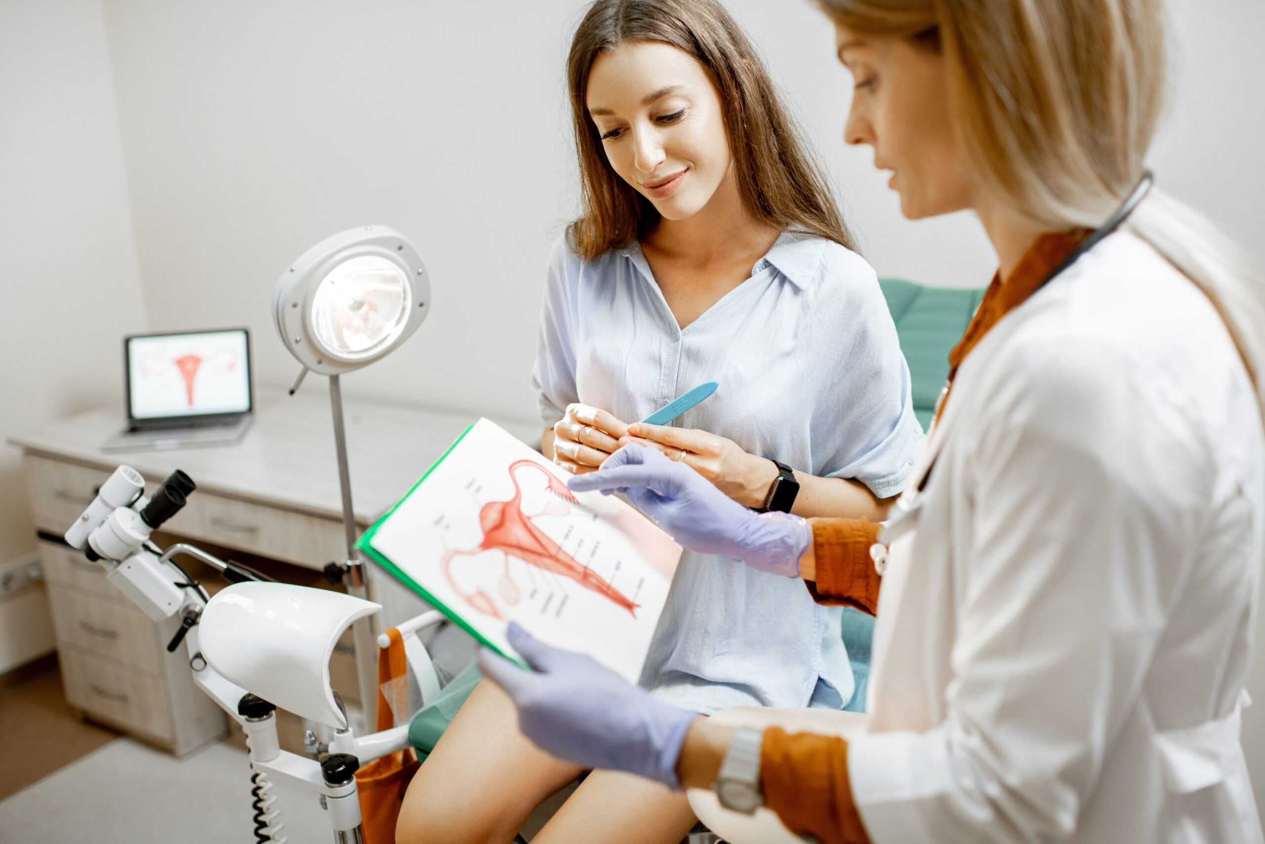 OB-GYN provider explaining Pap smear procedure to patient using diagram