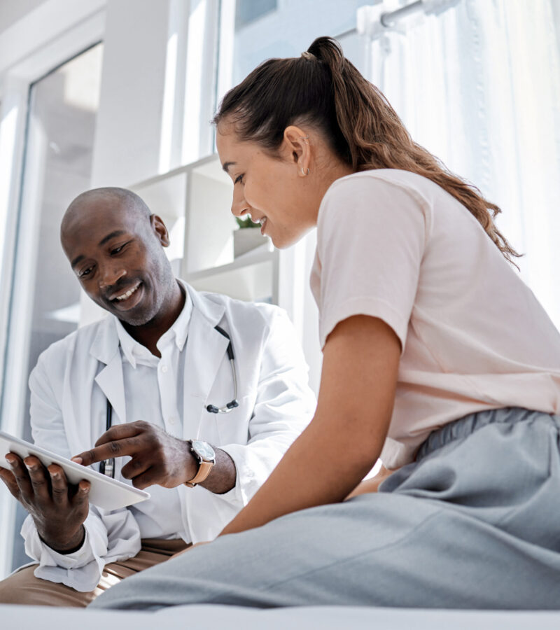 Doctor appointment or healthcare professional consulting a patient and showing her online medical results on a tablet. Medical worker or GP talking to a woman in a hospital or clinic